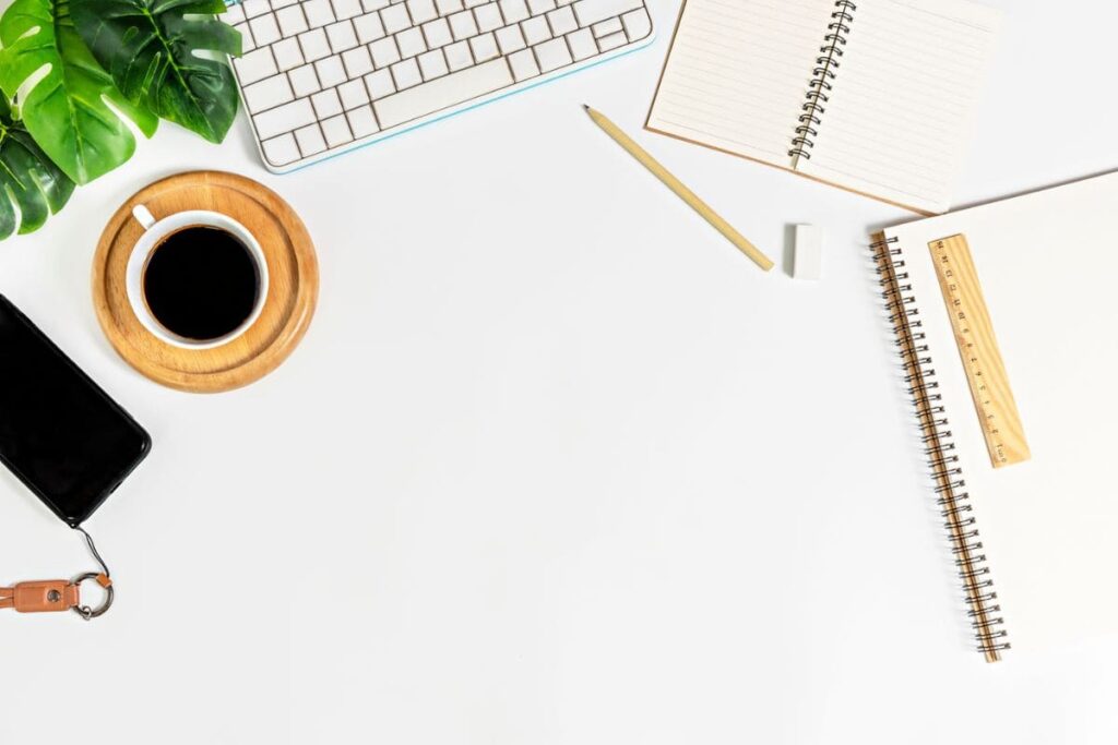 A home office desk, with a keyboard, coffee, and notebooks.