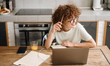 A happy, confident woman working from home on a laptop in her kitchen.