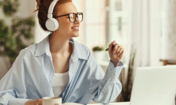 A work from home captioner wearing headphones and working on a computer.