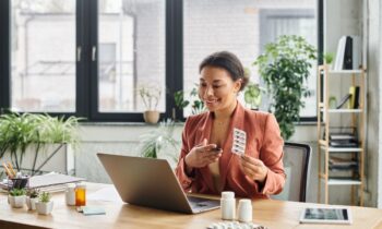 A female doctor, working from home, using a laptop to take a telehealth call and explain medication.