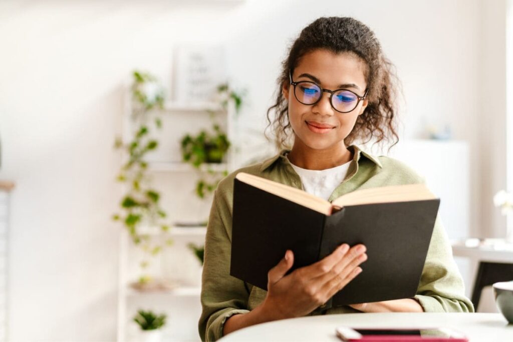 A woman business owner, sitting at a desk, reading a book.