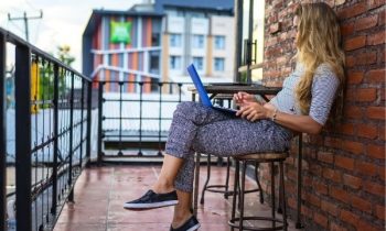 Woman job hunting on laptop in town at local cafe.