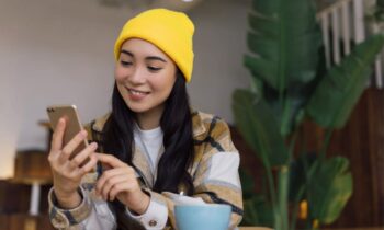 A young woman looking at social media on her phone in a coffee shop.