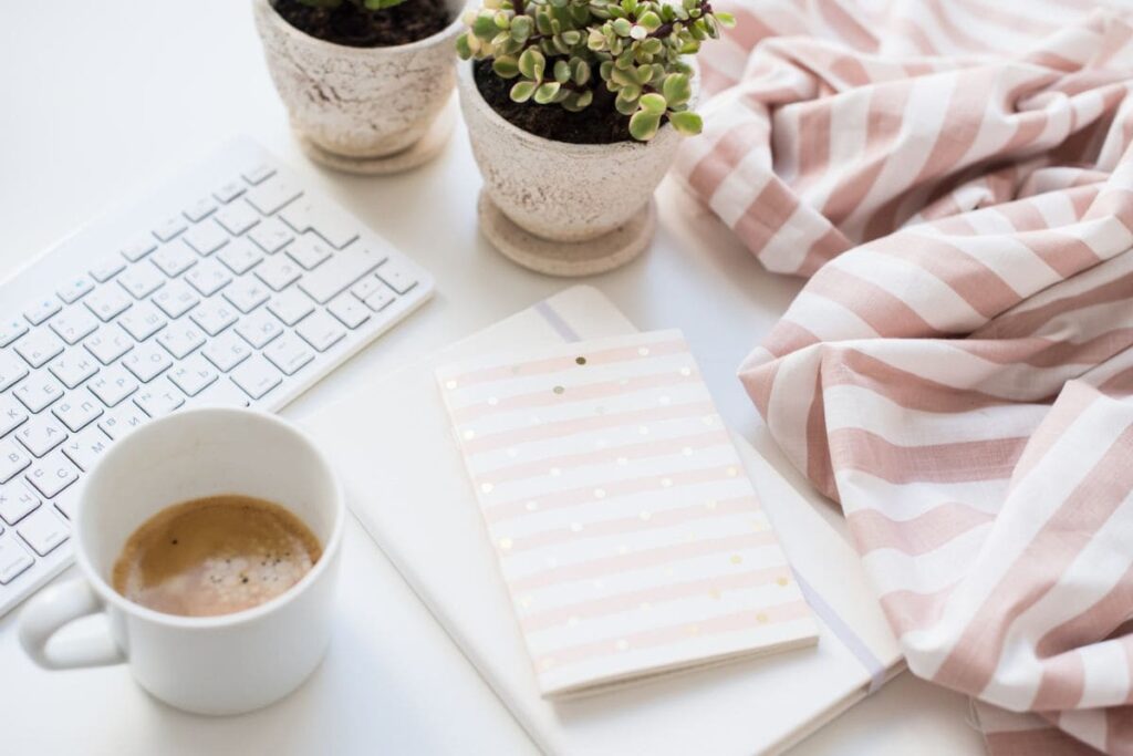 A home office workspace with a keyboard, notepad, and coffee.