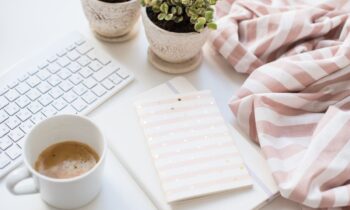 A home office workspace with a keyboard, notepad, and coffee.