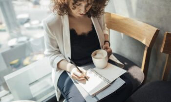 A product description writer working remotely from a cafe and drinking coffee.