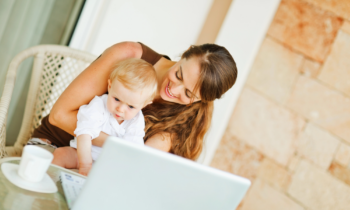 Baby sitting on mom's lap while she works on her summer work from home jobs