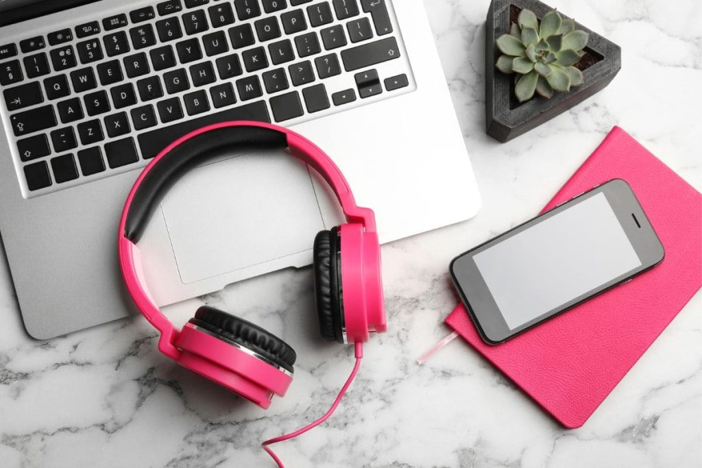 A work-from-home transcriptionist desk with a laptop, headphones, and a notebook.