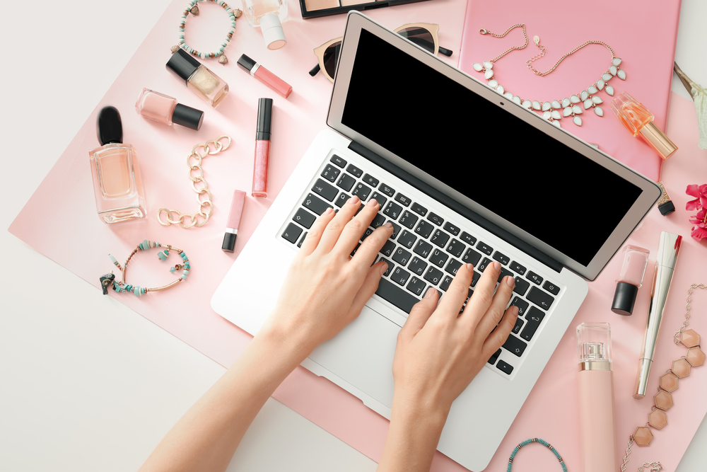 Female business owner working on laptop for her online retail makeup and jewelry business