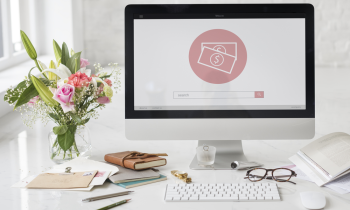 Home office space with flower, computer, books, and reading glasses