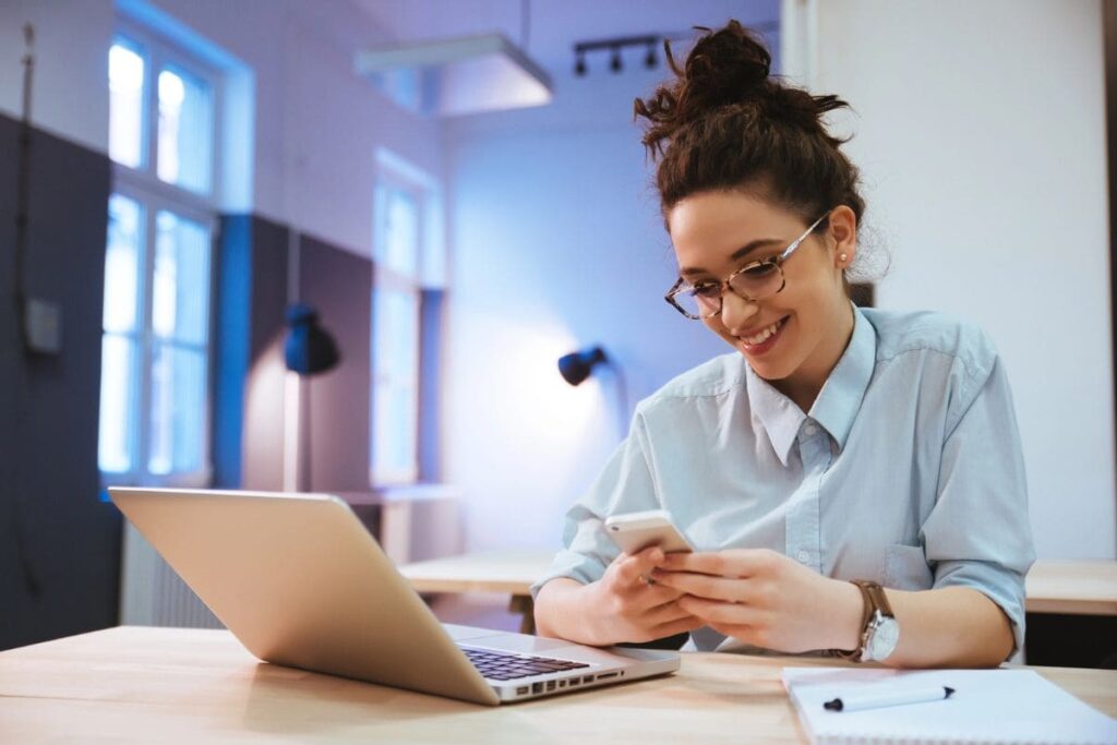 A woman working from home on her laptop and using her phone.