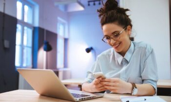 A woman working from home on her laptop and using her phone.