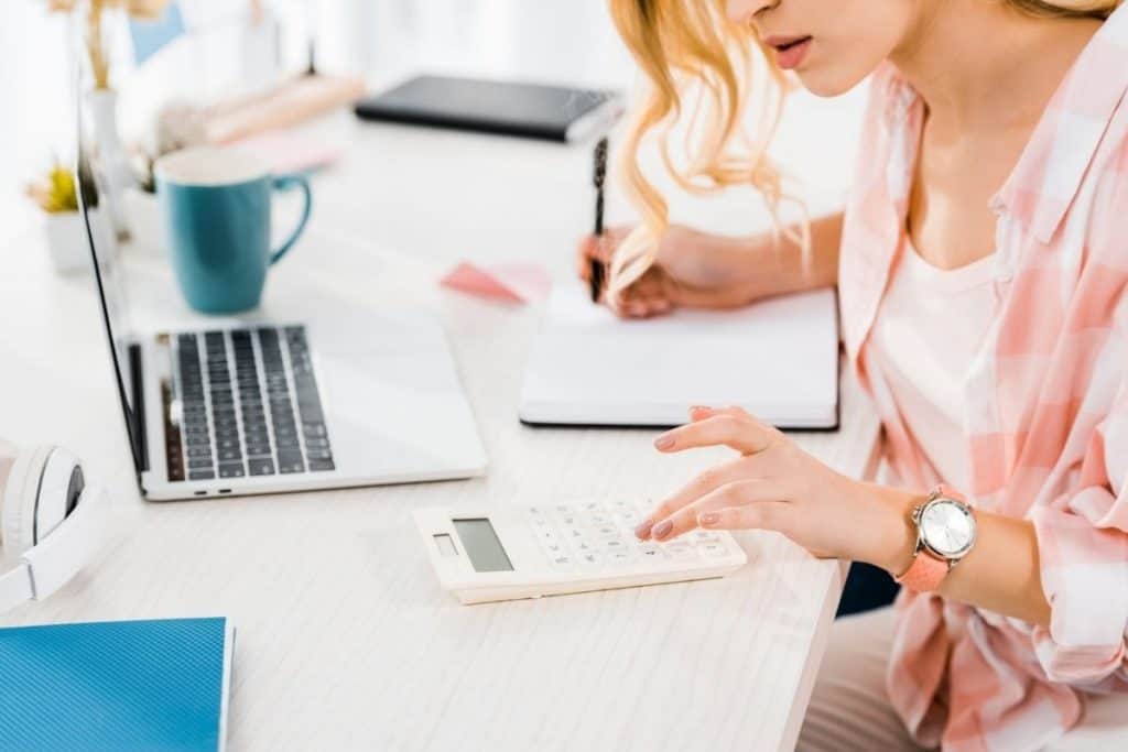 Woman sitting in home office, using a calculator and working on a budget