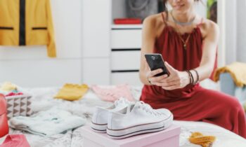 A woman cleaning out her closet and taking a picture of a pair of shoes to sell online on Facebook Marketplace.