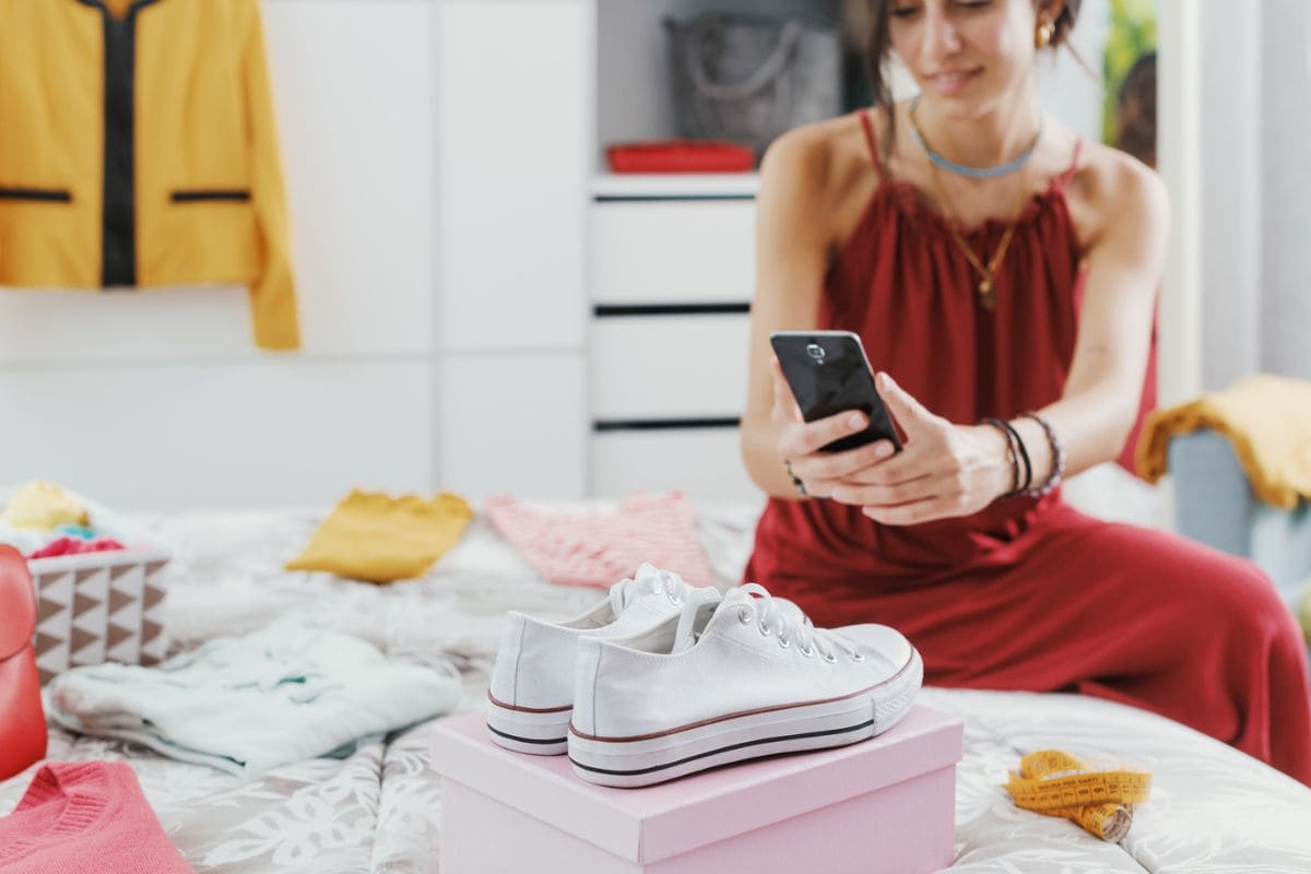 A woman cleaning out her closet and taking a picture of a pair of shoes to sell online on Facebook Marketplace.