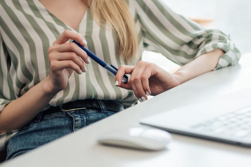 A woman sitting at a home office desk and using a laptop.