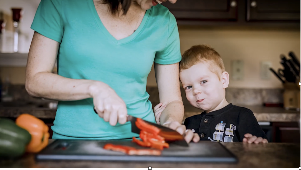 Mom cutting veggies while her son watches her for post FBI to home travel business