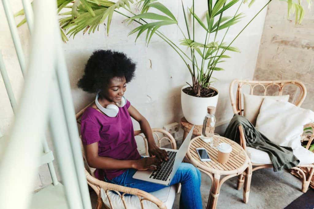 A 1099 freelancer working in a cafe on her laptop, wearing headphones.