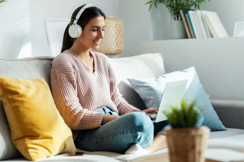 A woman working from home for Telus International, while sitting on the coach in her living room.