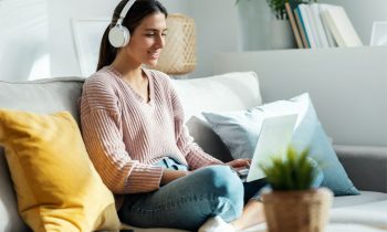 A woman working from home for Telus International, while sitting on the coach in her living room.