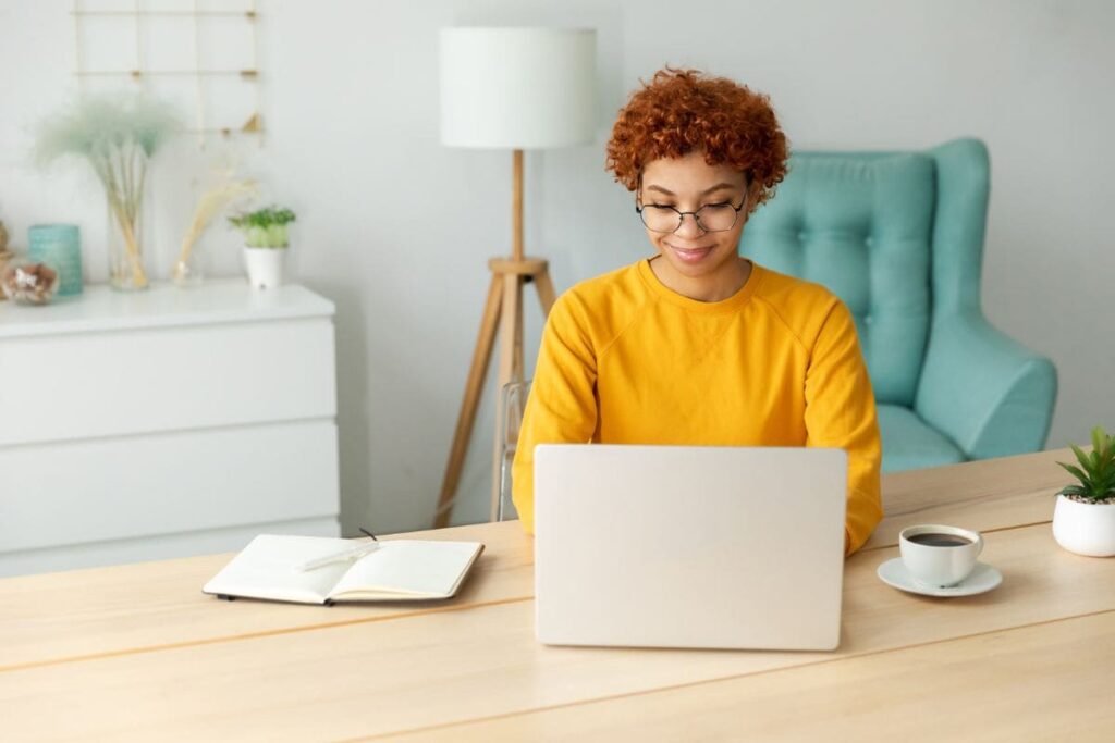 A woman working from home at a kitchen table.