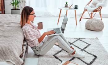 Woman drinking coffee working on her laptop at home doing her non-phone job