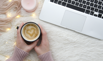 Woman holding a latte with a heart in it sitting at her desk