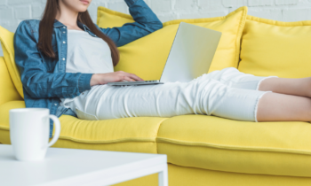 Woman sitting on her sofa looking at her laptop reading a User Interviews Review