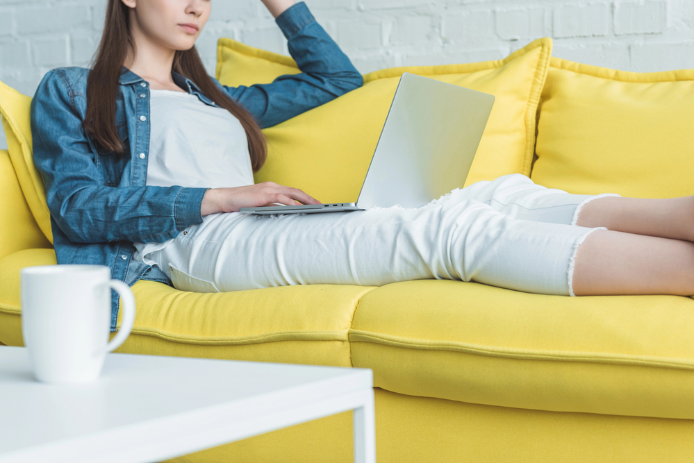 Woman sitting on her sofa looking at her laptop reading a User Interviews Review