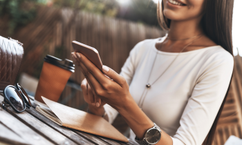 Woman taking paid surveys on smartphone while drinking coffee