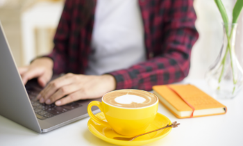 Woman using her laptop to take paid surveys online while drinking a latte