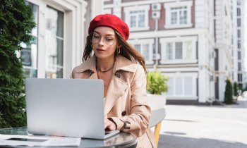 Woman wearing beret working on translation tasks on her laptop in France