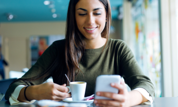 Woman with long hair drinking coffee in a cafe working her mobile phone job