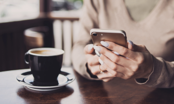 Woman with painted nails on cell phone drinking coffee