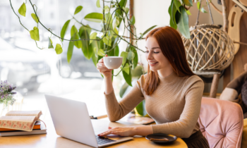 Woman with red long hair drinking coffee reading a FlexJobs Review online