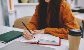 Woman writing in her notebook planning out her paid writing jobs