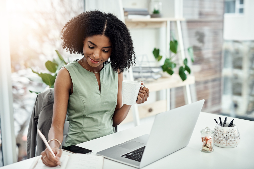 Young black woman writing in a notebook taking a free online course