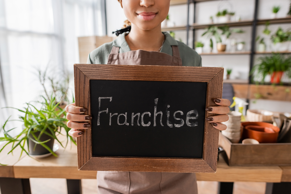 Young woman holding a chalkboard with the word franchise on it