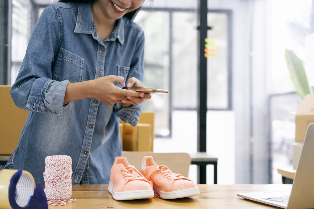 Young woman taking a photo of shoes she is selling online