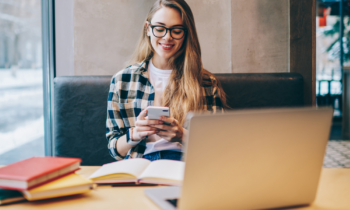 Young woman wearing glasses using her mobile phone to promote her blog on social media