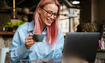 Young woman with glasses and pink hair looking at her laptop trying to get a work from home job