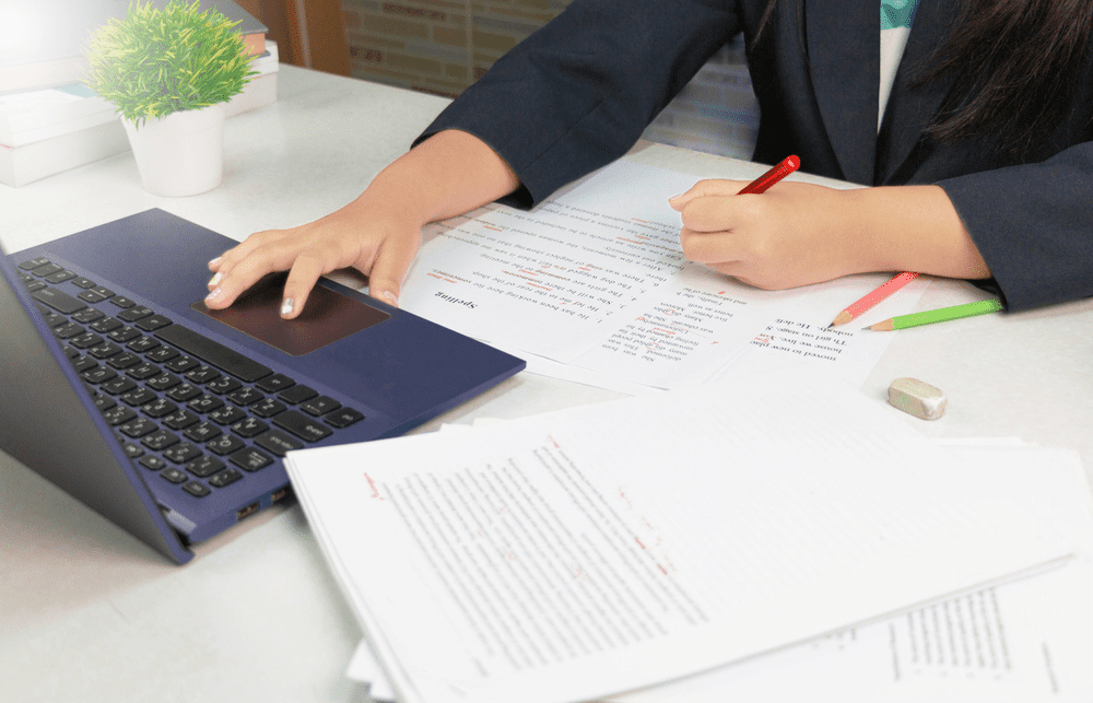 woman working on laptop and proofreading documents from home