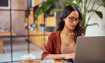 Young woman wearing glasses working on a laptop doing a review on UserTesting